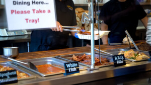 Meals being prepared by a worker in black shirt