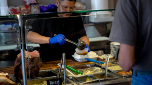 Meals being prepared by a worker in black shirt
