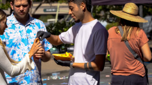 Man giving food samples to customers at outdoor market